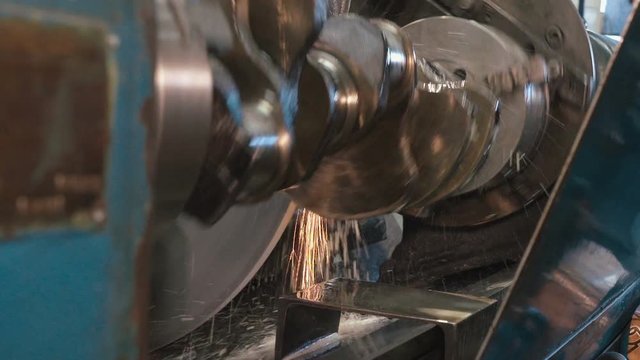 Close up of crankshaft on a grinding machine wheel operated by man hands, cooling emulsion flows, sparks flying. Shot with Sony a7s and Atomos Ninja Flame in shabby car service.
