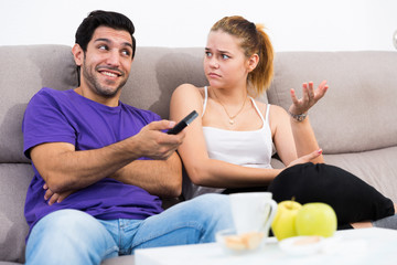 Fototapeta na wymiar Woman trying to take away TV remote from boyfriend