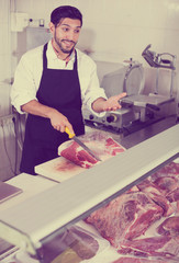 Portrait of adult man butcher is cutting meat
