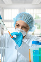 Young female tech or scientist loads liquid sample into test tube