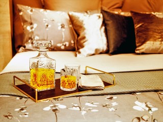Decanter and glasses with whiskey on the bed