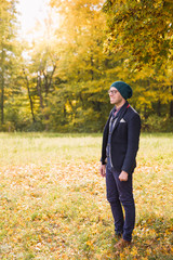 The young man standing in the park and smiling