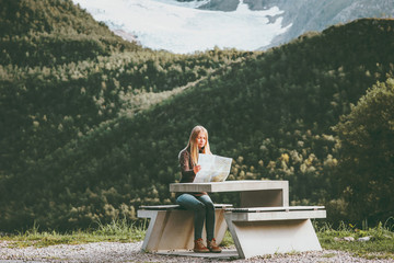 Fototapeta premium Young Woman holding map planning journey route in Norway sitting at the table Travel Lifestyle concept adventure vacations outdoor