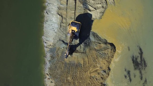 Aerial view, total scene, camera flying to the sandbank in the middle of the river, earth movers using hydraulic shovel to digging sand, forest coast, sunny day.