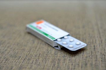 Fototapeta premium White pills spilling out of a toppled bright red orange pill bottle