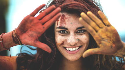 Young woman holding paint covered hands up to her face