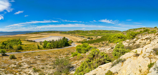 Panoramabild von der wunderschönen Landschaft in der Region um die kleine französische Ortschaft Gruissan mit seinen Hügeln, Felsen und Weinreben und dem Blick auf das Mittelmeer in Südfrankreich