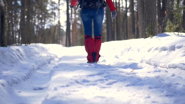 Female hiker legs walking on a snow road.