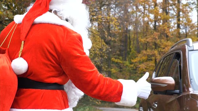 Back side view of Santa Claus hitchhiking on the road in forest 50 fps