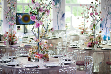 Fototapeta na wymiar Tender pink peonies in the glass vase on little round dinner tables in the restaurant