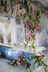 Fototapeta na wymiar Blue dinner table for newlyweds decorated with hanging colorful flowers