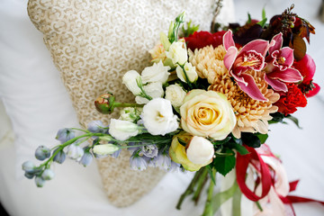 Bouquet of white roses, lilies and chrysanthemums lies on the bed