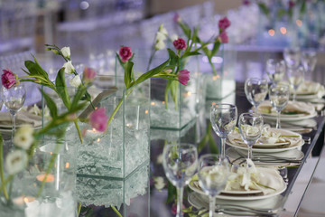 Pink peony put in a glass box with candle stands on dinner table