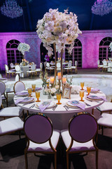 Look from behind round chairs at dinner table decorated with large bouquet of roses