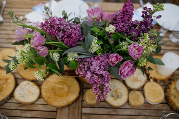 Bouquet of violet lilac and tulips stands on the wooden decor on the table