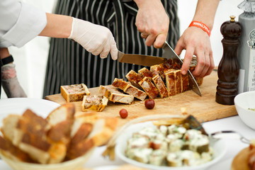 Man cuts bread with cheese and meat
