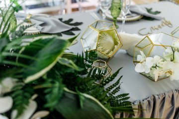 Golden cubes with white flowers stand on grey table for newlyweds