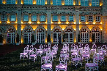 White chairs with pink seats stand on the backyard