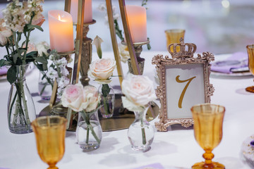 Steel frame with number seven stands on dinner table with golden glasses