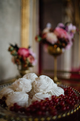 White cookies and red berries on golden dish