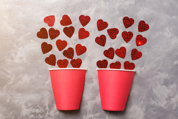 Creative valentines card. Two half of paper cup are fill up by red papers hearts, minimal concept, flat layout.