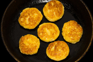 Fried curd cheese pancakes, cheesecakes in frying pan, close up view