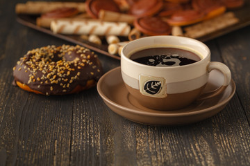 Cups of tea and chocolate donuts on a black background.