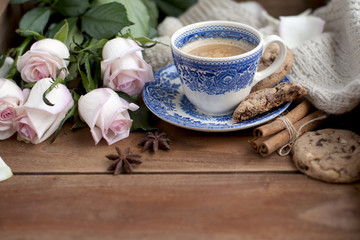 Fototapeta na wymiar coffee in a vintage cup, on a wooden background and a bouquet of white roses