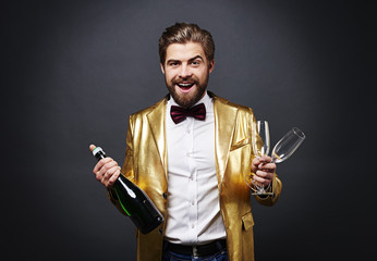 Cheerful man holding bottle of champagne and champagne flute © gpointstudio