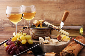Gourmet Swiss fondue dinner on a winter evening with assorted cheeses on a board alongside a heated...