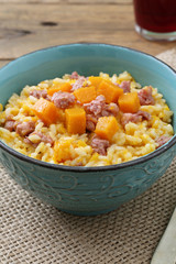 risotto italiano con zucca gialla e salsiccia su sfondo rustico