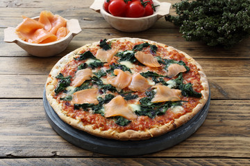 pizza con pesce salmone affumicato e spinaci su sfondo rustico