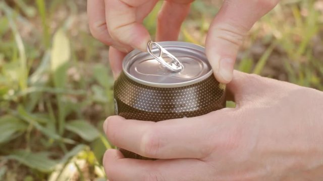 Female teenager opens can with drink outdoors