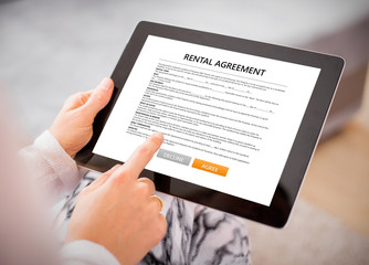 Woman reading rental agreement on tablet.