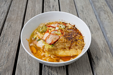 Egg noodle soup with roasted pork and crispy wonton, Thai style spicy noodle soup on wood background