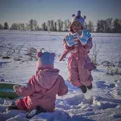 Dwie małe siostry bawią się na śniegu. - obrazy, fototapety, plakaty