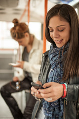 Young girl uses a mobile phone in the city bus