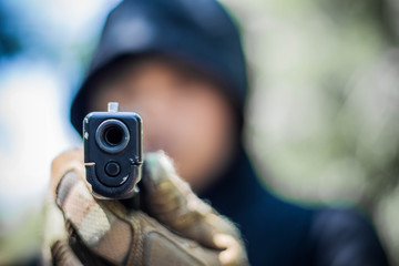 Terrorist or gunman wearing a mask and holding a gun ready to fire