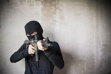 Terrorist or gunman wearing a mask and holding a gun ready to fire