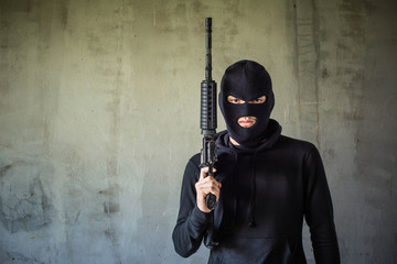 Terrorist or gunman wearing a mask and holding a gun ready to fire