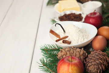 Baking ingredients. eggs, butter, spice, apples, raisins, vanilla and cinnamon sticks, white flour and xmas tree on white wooden table background. copy space, new year, xmas, food concept
