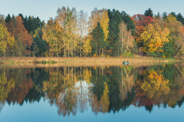 Farewell to Autumn as the final leaf-fall has begun. Sunny October day at Āraiši lake with stunning mirror reflections in water. 