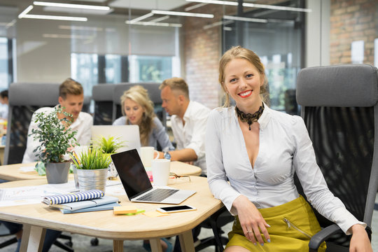 Happy woman sitting with co -workers