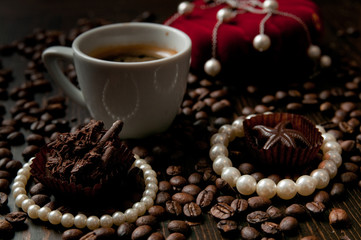 cup of coffee with a gift necklace and coffee beans in background and a red luxury box with jewlery