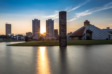 sun between buildings at dawn of the lake - obrazy, fototapety, plakaty