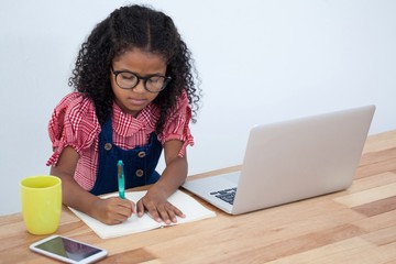 High angle view of businesswoman writing on book by laptop