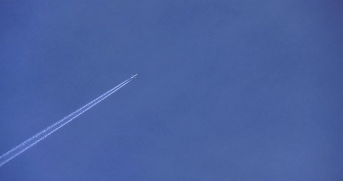 Linear airplane swings fast in the blue sky with a white trail of water vapor and exhaust gas engines