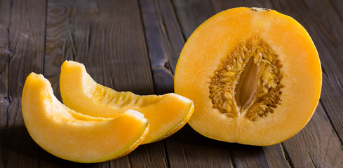 Half melon and slices on a dark wooden background