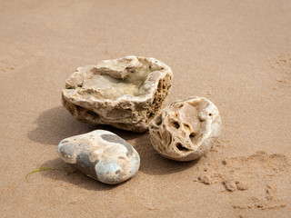 Fototapeta na wymiar Three small stones lying on a sand beach