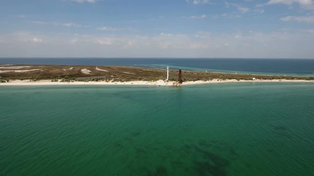 A striking bird`s eye view of a white lighthouse and a high border tower on Dzharylhach island with wild seashore covered with dark wetland and white sand in summer. The skyscape is marvelous